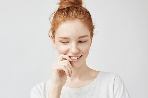Portrait of shy beautiful woman with foxy hair and freckles smiling.