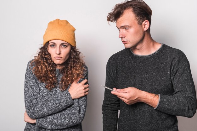 Portrait of sick couple holding thermometer and pills with water