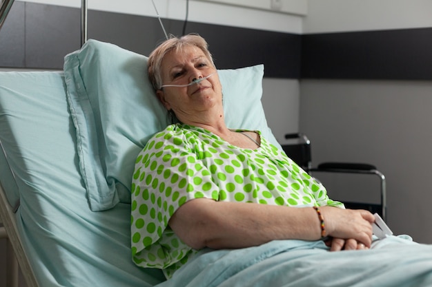 Ritratto di donna pensionata malata che guarda nella telecamera mentre riposa a letto