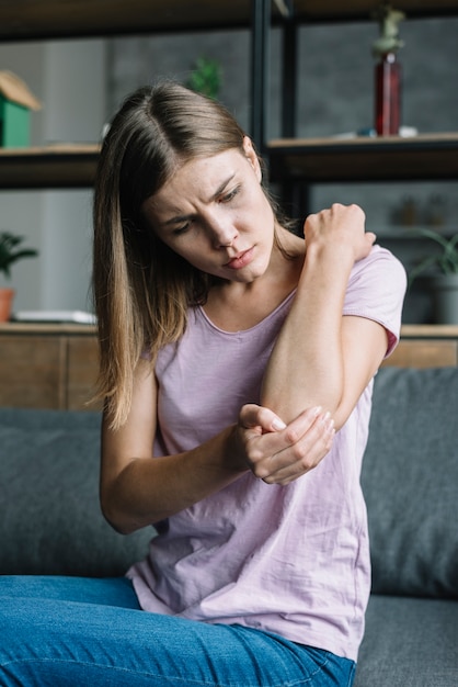 Free photo portrait of a sick young woman touching her elbow