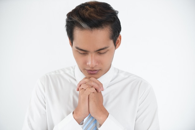 Portrait of silent young Asian businessman praying