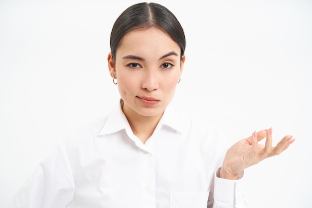 Free photo portrait of skeptical asian woman looks unamused and serious at camera stands isolated on white back