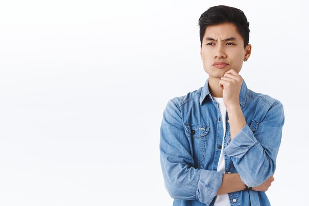 Portrait of skeptical man thinking making choice facing decision and being displeased with it smirk disappointed looking away while pondering something standing white background judgemental