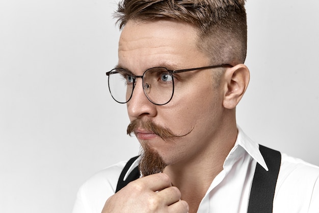 Portrait of smart elegant young European businessman in stylish eyeglasses and formal wear
