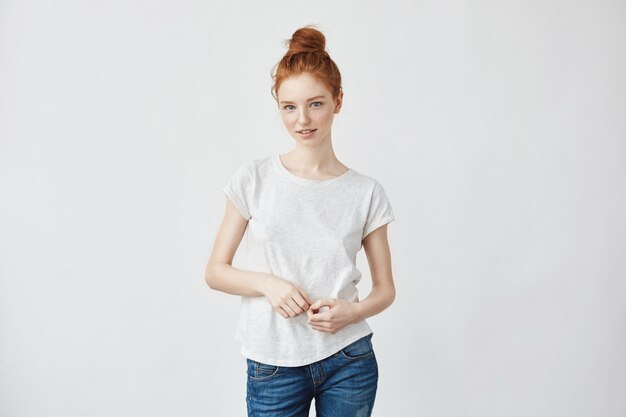 Portrait of smart redhead woman flirting feeling insecure yet to meet her boyfriend. Weating jeans and a bun