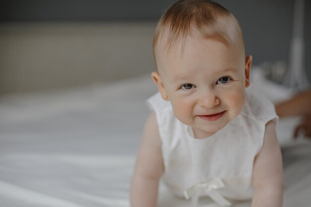 Portrait of smiled wondered little cute baby girl with big eyes crawling on the white background, funny tiny kid.