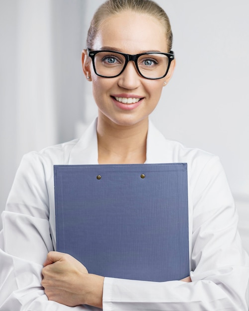 Free photo portrait of smiley female researcher in the lab with clipboard