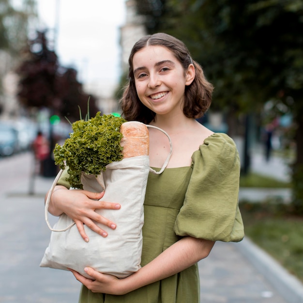 Foto gratuita ritratto di donna sorridente che trasportano generi alimentari