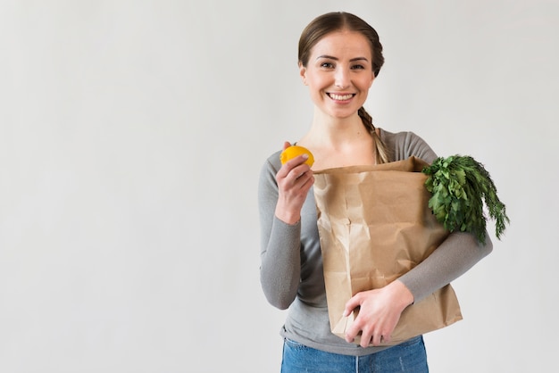 Free photo portrait of smiley woman holding paper bag with groceries