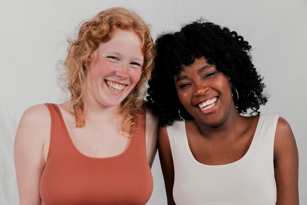 Portrait of a smiling african and blonde young women against grey background