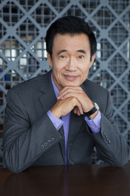 Free photo portrait of smiling asian man with hands on chin