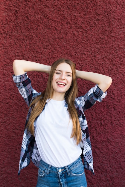 Ritratto della donna attraente sorridente che posa vicino al muro ruvido