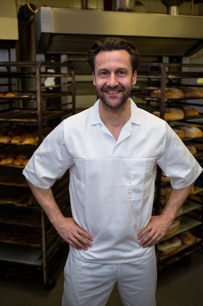 Portrait of smiling baker standing with hands on hip