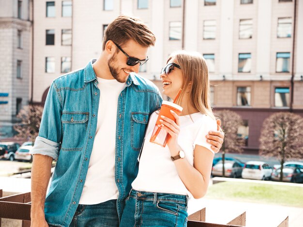 Portrait of smiling beautiful girl and her handsome boyfriend in casual summer clothes.   . Woman with bottle of water and straw