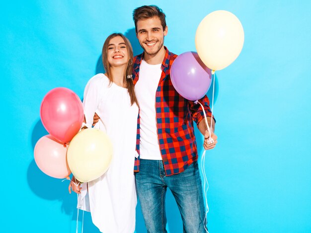 Portrait of Smiling Beautiful Girl and her Handsome Boyfriend holding bunch of colorful balloons and laughing. Happy Birthday