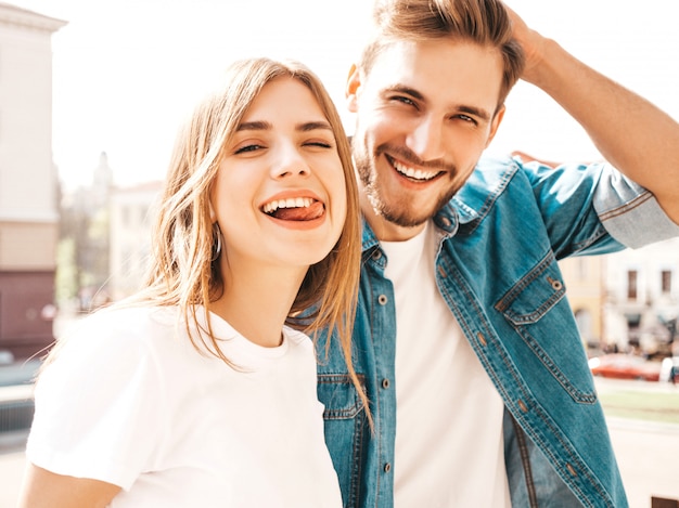 Portrait of smiling beautiful girl and her handsome boyfriend. Woman in casual summer jeans clothes.  . Shows tongue