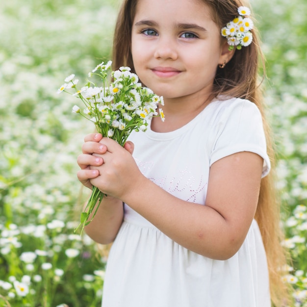野生の花を握っている笑顔の美しい少女