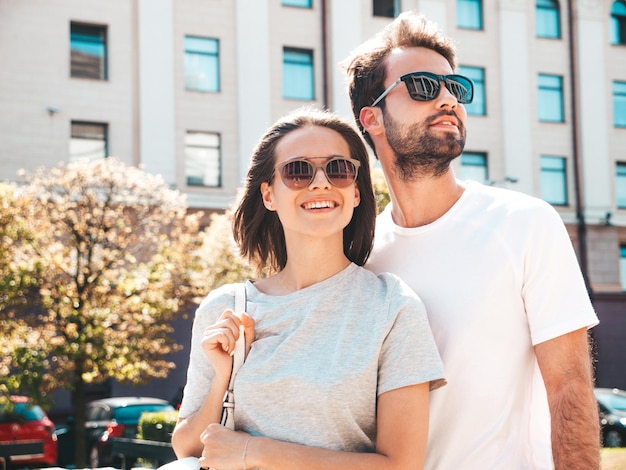 Portrait of smiling beautiful woman and her handsome boyfriend Woman in casual summer clothes Happy cheerful family Female having fun Couple posing on the street background in sunglasses