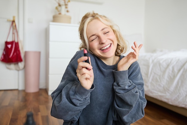 彼女の部屋で笑顔の美しい女性の肖像画が座って,リップスティックを示し,お気に入りを推奨しています