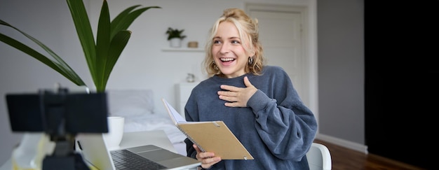 Portrait of smiling beautiful young blond woman student working on assignment from home online
