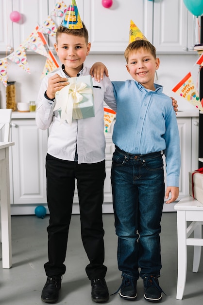 Portrait of a smiling birthday boy standing with his friend in the kitchen