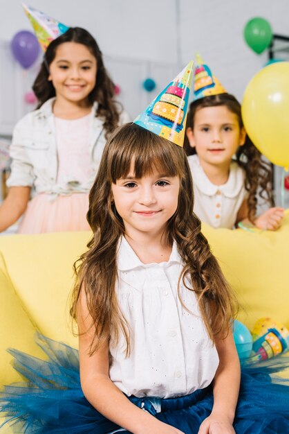 Portrait of smiling birthday girl with blur friends standing behind her