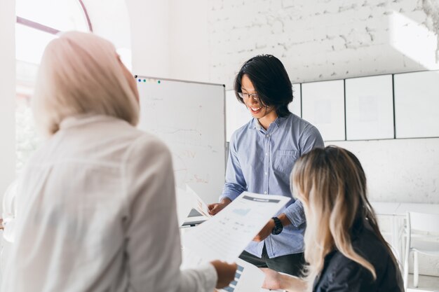 前景に白いシャツを着た金髪の女性と眼鏡をかけて笑顔の黒髪の学生の肖像画