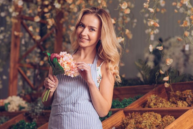 Portrait of smiling blonde female florist holding flower bouquet in hand