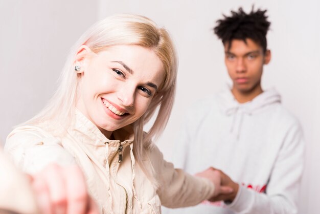 Portrait of smiling blonde young woman holding hands of her boyfriend