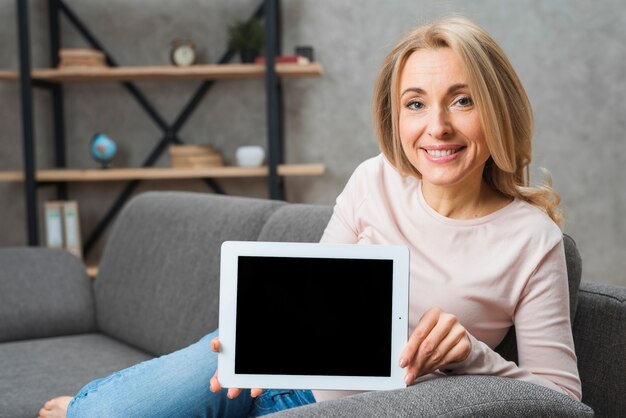 Portrait of a smiling blonde young woman showing digital tablet screen