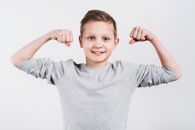 Portrait of a smiling boy clenching his fist looking to camera standing against grey background
