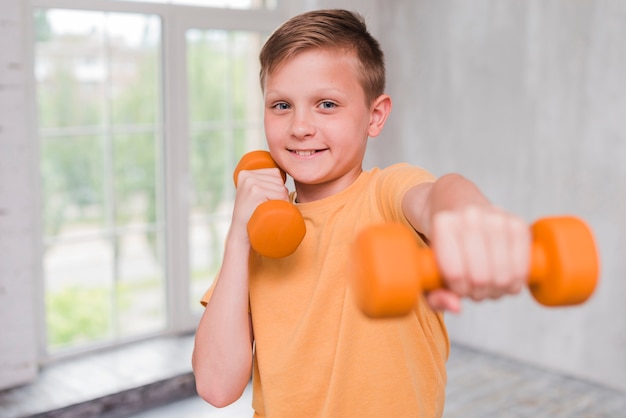 Ritratto di un ragazzo sorridente che si esercita con il dumbbell