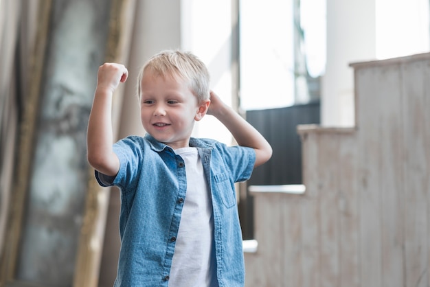 Free photo portrait of a smiling boy flexing his muscle