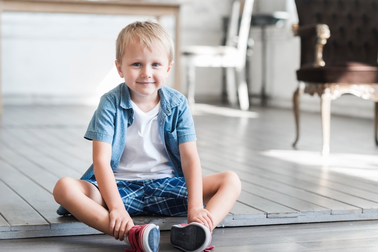 Free Photo portrait of a smiling boy sitting on floor at home