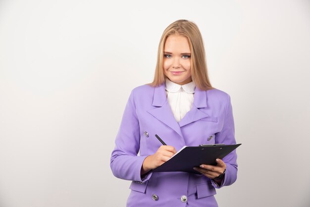 Portrait of smiling business woman standing and holding clipboard.