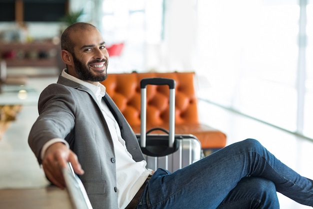 Portrait of smiling businessman sitting on chair in waiting area