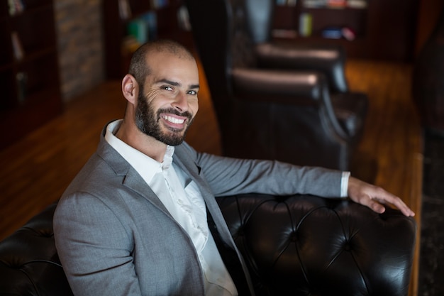 Portrait of smiling businessman sitting on sofa in waiting area