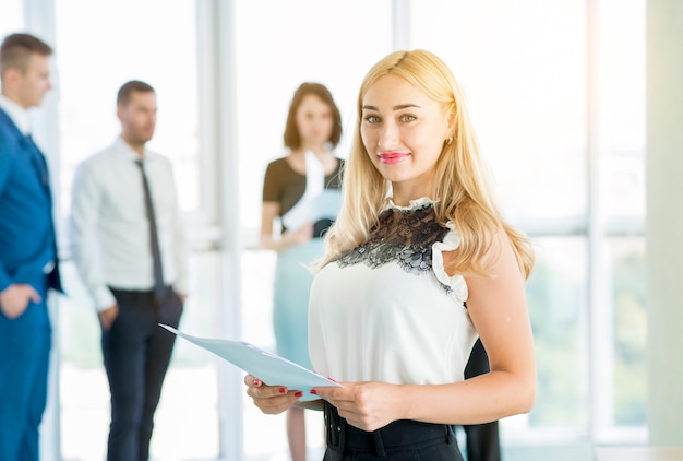 Free photo portrait of a smiling businesswoman holding document in office