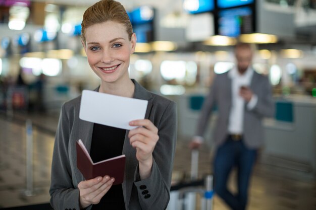 Portrait of smiling businesswoman showing her boarding pass