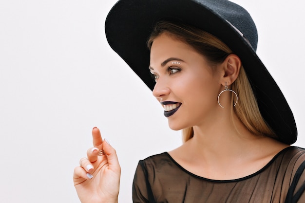 Portrait of smiling charming woman with black lipstick and black hat