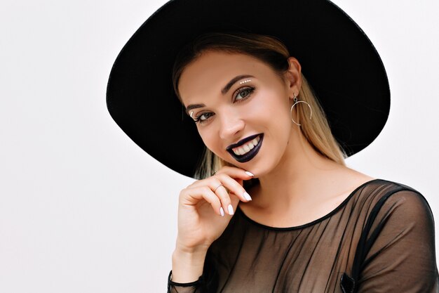 Portrait of smiling charming woman with black lipstick and black hat