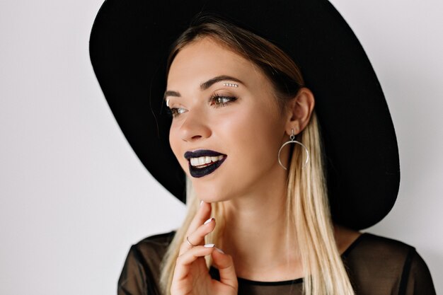 Portrait of smiling charming woman with black lipstick and black hat