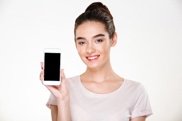 Portrait of smiling content woman demonstrating efficient cell phone showing screen