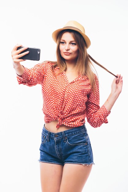 Portrait of a smiling cute woman making selfie photo on smartphone isolated on a white background