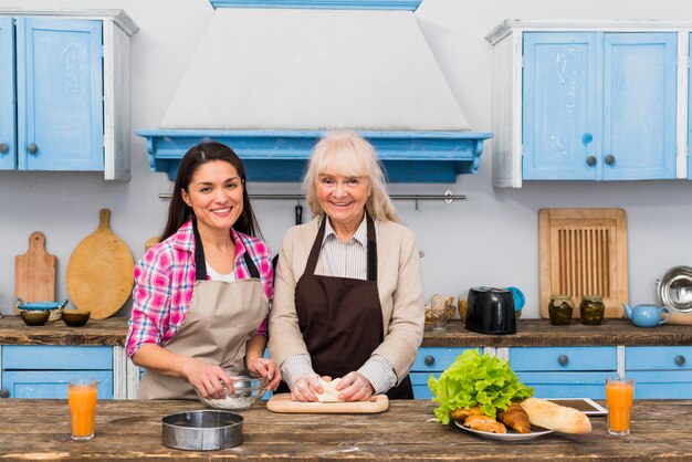 Portrait of smiling daughter and her mother preparing food in the kitchen