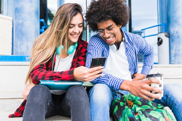 Portrait of smiling diverse young students looking at mobile phone