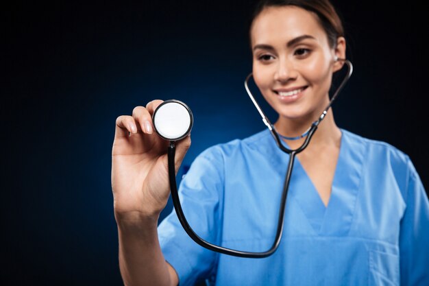 Portrait of smiling doctor in blue uniform using stethoscope