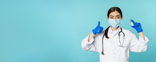 Foto gratuita ritratto di medico sorridente personale medico in maschera medica facciale e guanti di gomma che mostrano i pollici in su