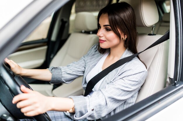 Portrait of smiling driver woman fastening her seatbelt before driving a car.