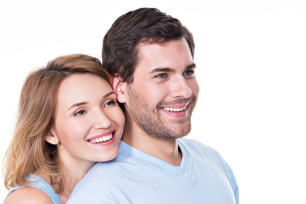 Portrait of smiling embracing couple in casual looking  sideways -  isolated